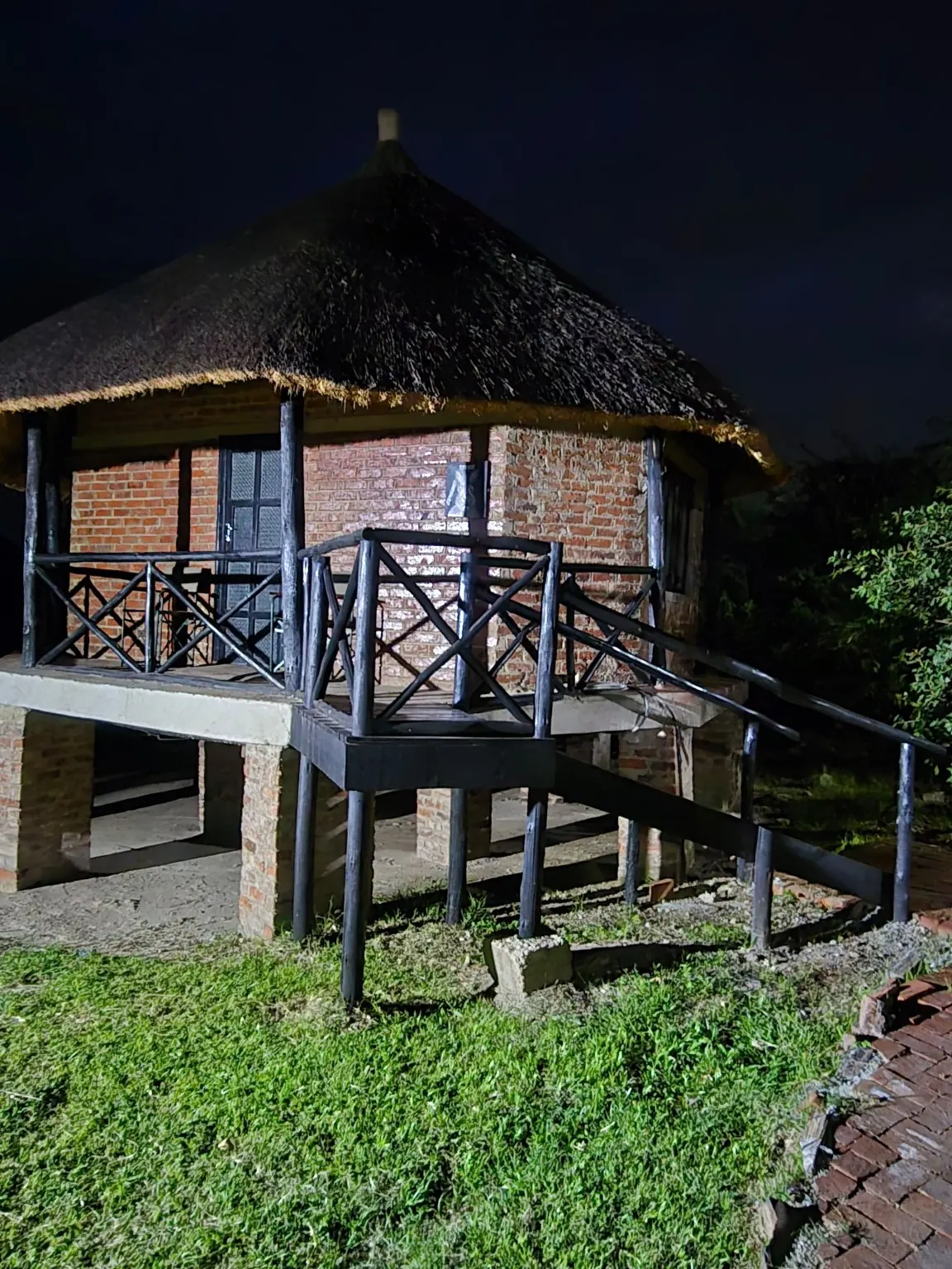 Brick-and-thatch chalet raised on stilts, lit against the night sky