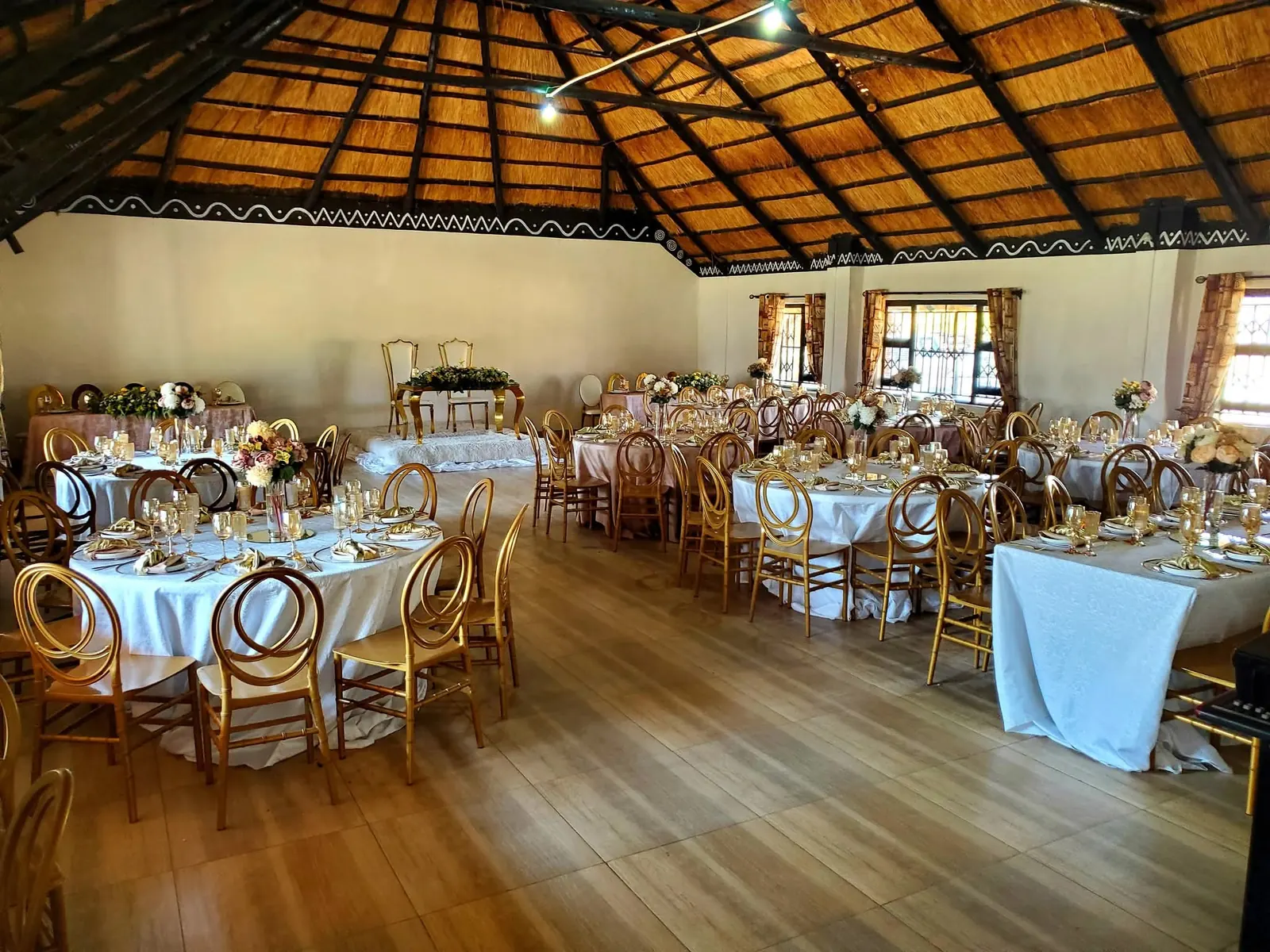 Thatched hall with round tables laid for an event