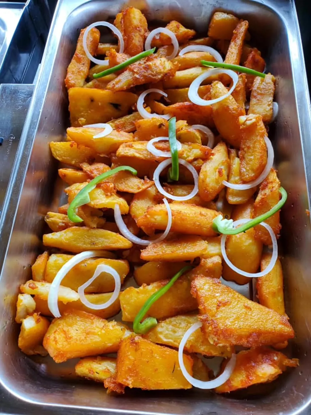 Tray of potato wedges with onion and green pepper