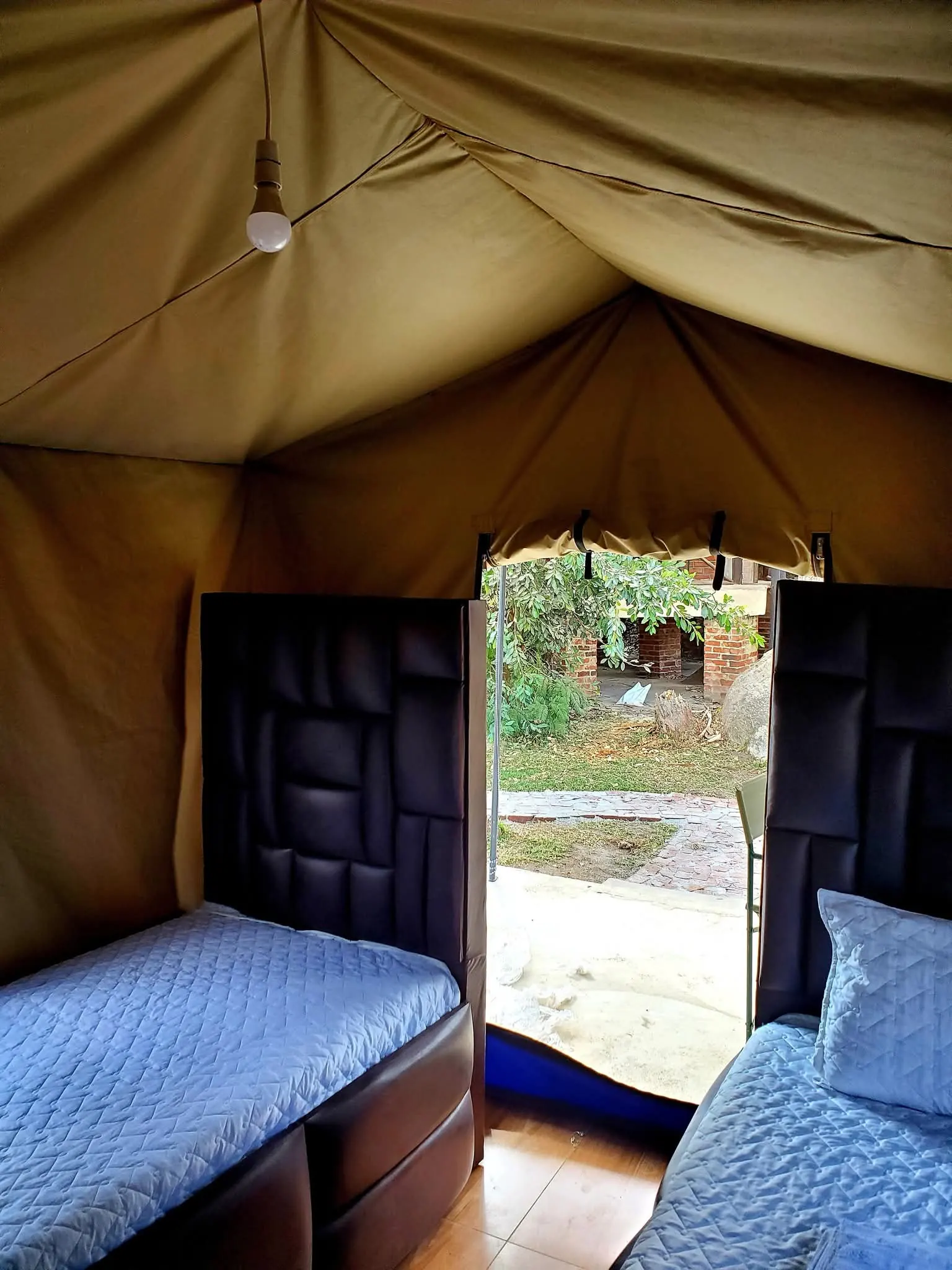 Tented room with a bed and an open door looking out onto the grounds
