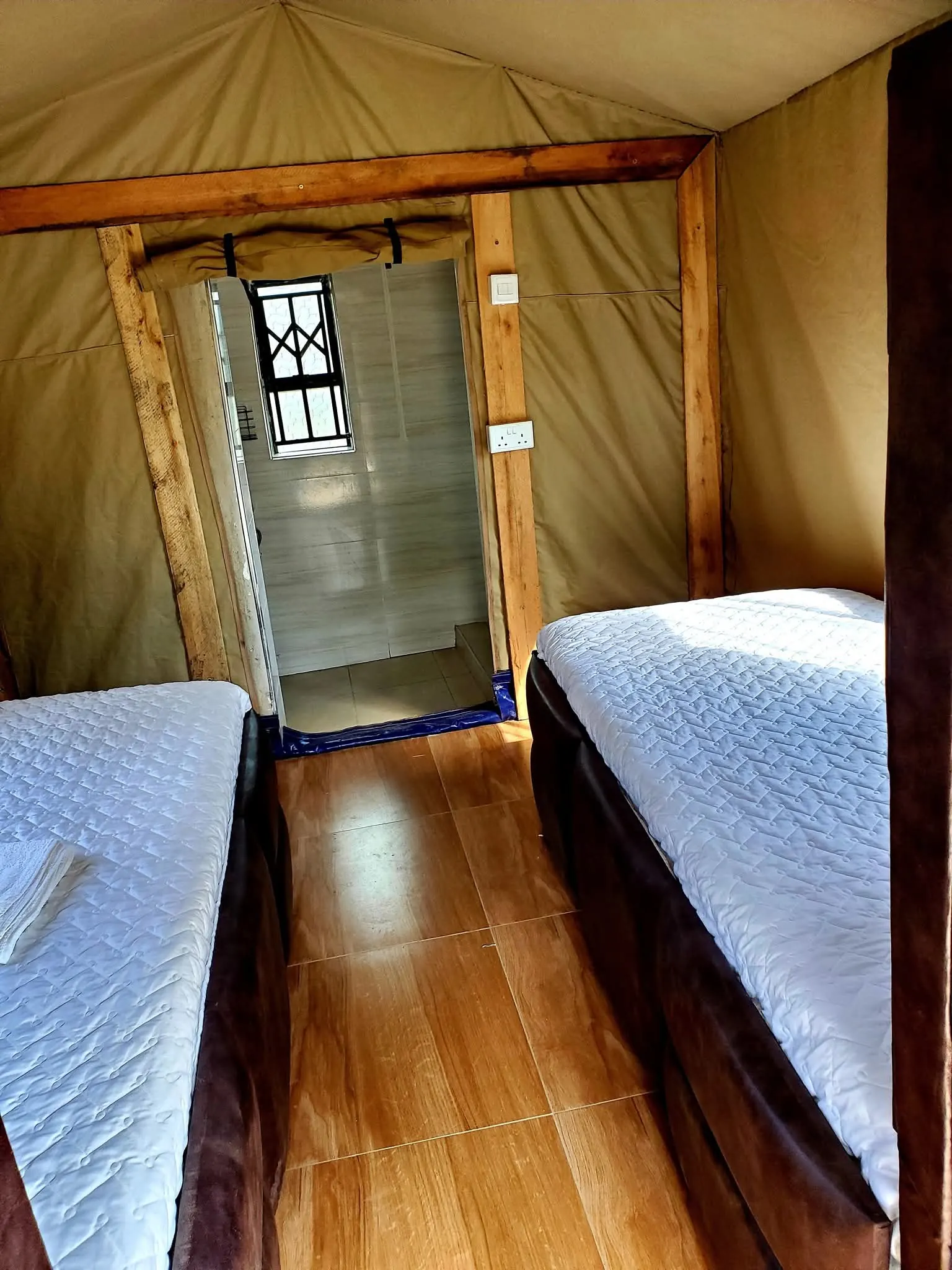Tented room with two single beds and a doorway to the bathroom