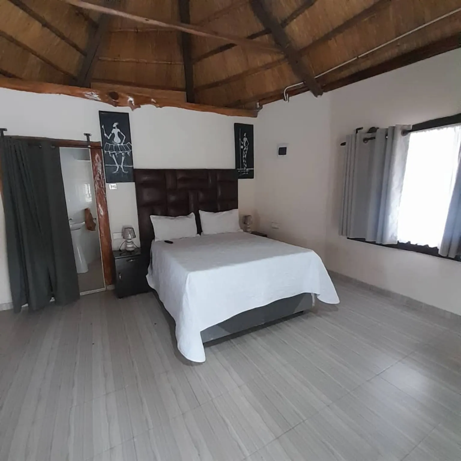 Thatched-roof room with a double bed and private bathroom