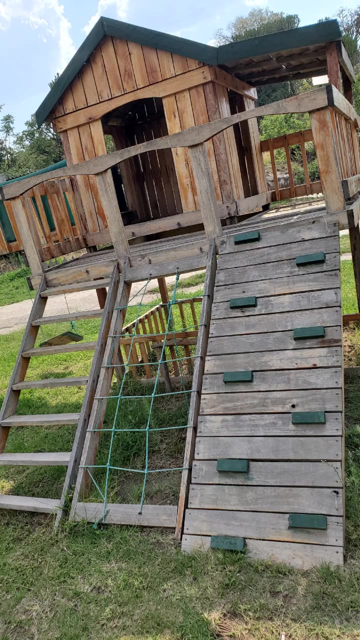 Wooden climbing frame, swings, trampoline and slide on the lawn